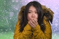 Beautiful Asian Korean woman feeling cold and chilly freezing feeling cold in Winter weather wearing yellow jacket with fur hood Royalty Free Stock Photo