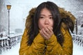 Beautiful Asian Korean woman feeling cold and chilly freezing feeling cold in Winter weather wearing yellow jacket with fur hood Royalty Free Stock Photo