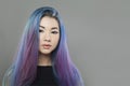 Beautiful Asian model woman with bright colored blue and purple hair looking at camera on gray background, portrait Royalty Free Stock Photo