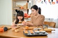 Beautiful Asian mom and her daughter are making Halloween cupcakes. Halloween day concept Royalty Free Stock Photo