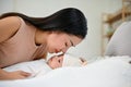 Beautiful asian mom lay down with her baby, comforting her son on bed Royalty Free Stock Photo