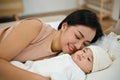 Beautiful asian mom lay down with her baby, comforting her son on bed Royalty Free Stock Photo