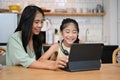 Beautiful asian mom and lovely daughter looking at tablet screen together Royalty Free Stock Photo