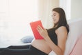 Beautiful asian mom or pregnant woman reading book that the book give some knowledge about prenatal care of her infant and mother Royalty Free Stock Photo
