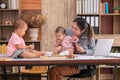 Beautiful Asian mother confuse multi task, single mom cannot work while kids playing, work from home fussy taking care chaotic Royalty Free Stock Photo