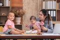 Beautiful Asian mother confuse multi task, single mom cannot work while kids playing, work from home fussy taking care chaotic Royalty Free Stock Photo