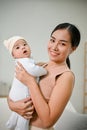 Beautiful Asian Mother holding her baby boy while relaxing in the living room Royalty Free Stock Photo