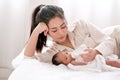 Beautiful Asian mother lie on white bed and give milk to her newborn baby Royalty Free Stock Photo