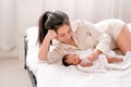 Beautiful Asian mother lie on white bed and give milk to her newborn baby Royalty Free Stock Photo