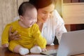 Beautiful Asian mother spent time with curiosity toddler baby boy talking, playing on workplace home, adorable naughty son happy Royalty Free Stock Photo