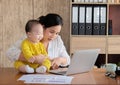Beautiful Asian mother spent time with curiosity toddler baby talking, playing at workplace home, adorable naughty son happy Royalty Free Stock Photo