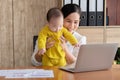 Beautiful Asian mother spent time with toddler baby boy talking, playing on workplace, adorable naughty son happy laughing on Royalty Free Stock Photo