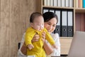 Beautiful Asian mother spent time with toddler baby boy talking, playing on workplace, adorable naughty son happy laughing on Royalty Free Stock Photo