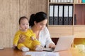 Beautiful Asian mother spent time with toddler baby boy talking, playing on workplace, adorable naughty son happy laughing on Royalty Free Stock Photo