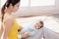 Beautiful Asian mother talking with toddler while baby lying on mother`s lap, young mom bonding with her adorable little baby at Royalty Free Stock Photo