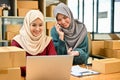 A beautiful Asian Muslim female online seller is talking on the phone with a supplier Royalty Free Stock Photo