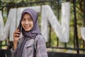 beautiful asian muslim student calling her friend using smartphone in park Royalty Free Stock Photo