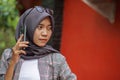 beautiful asian muslim student calling someone using smartphone in park Royalty Free Stock Photo