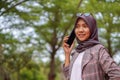 beautiful hijab muslim student calling her friend using smartphone in park Royalty Free Stock Photo
