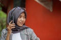 beautiful asian muslim hijab student calling someone using smartphone in park Royalty Free Stock Photo