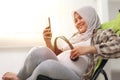 Beautiful Asian muslim pregnant puts the headphone on her tummy and opens Quran recitation or classical music for her baby