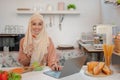 A beautiful Asian Muslim woman is eating her healthy salad while working on her laptop Royalty Free Stock Photo