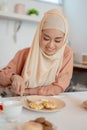 A beautiful Asian Muslim woman eating waffles, having her breakfast at a table in the kitchen Royalty Free Stock Photo