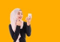 Beautiful Asian muslim woman in hijab standing holding mirror and applying pink lipstick on her lips isolated on yellow background Royalty Free Stock Photo