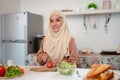 A beautiful Asian Muslim woman is preparing ingredients for her healthy salad mix in a kitchen Royalty Free Stock Photo