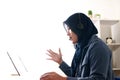 Beautiful Asian muslim woman using headphones speaking her laptop, explaining something. Professional teacher mentor customer Royalty Free Stock Photo