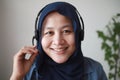 Beautiful Asian muslim woman using headphones speaking to camera, explaining something. Professional teacher mentor customer Royalty Free Stock Photo