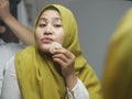 Beautiful Asian muslim woman wearing hijab and applying makeup Royalty Free Stock Photo