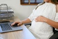 Beautiful Asian pregnant businesswoman working at her desk, using laptop. cropped shot Royalty Free Stock Photo