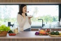 Beautiful Asian pregnant woman eating with lust cereals on breakfast in kitchen at home, enjoying meal. Yummy food for pregnant