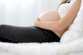Beautiful Asian pregnant woman lie on bed and use hand touch belly with carefully emotion. Concept of good healthy activity for Royalty Free Stock Photo