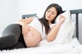 Beautiful Asian pregnant woman lie with relax position and use one hand touch her belly. Concept of good healthy activity for Royalty Free Stock Photo