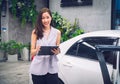 Beautiful Asian saleswoman standing nearby a new car. Car dealership concept