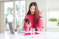 Beautiful Asian student woman using laptop and smartphone very happy and excited, winner expression celebrating victory screaming Royalty Free Stock Photo