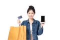 Beautiful Asian stylish young woman in jeans shirt is holding shopping bags, smartphone, credit card and smiling isolated on white Royalty Free Stock Photo