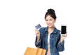 Beautiful Asian stylish young woman in jeans shirt is holding shopping bags, smartphone, credit card and smiling isolated on white Royalty Free Stock Photo