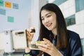 Beautiful asian thai long dark hair woman doing healthy food vlog with smartphone at office desk. City background
