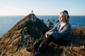 Beautiful asian tourist chilling out at Nugget Point, Dunedin, New Zealand. Young asian traveller enjoys coffee in morning at