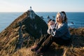 Beautiful asian tourist chilling out at Nugget Point, Dunedin, New Zealand. Young asian traveller enjoys coffee in morning at