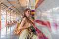 Beautiful asian traveler with backpack getting on a train at a platform of railway station Royalty Free Stock Photo