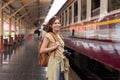 Beautiful asian traveler with backpack getting on a train at a platform of railway station Royalty Free Stock Photo