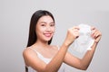 Beautiful asian woman applying paper sheet mask on her face whit