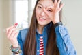 Beautiful Asian woman applying red lipstick on lips with happy face smiling doing ok sign with hand on eye looking through fingers Royalty Free Stock Photo