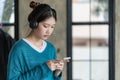 Beautiful Asian woman in casual clothes sitting on sofa using smartphone for social entertainment to relax. smile and laugh