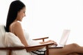 Beautiful asian woman in casual wear sitting on arm chair using laptop computer in a cozy living room Royalty Free Stock Photo