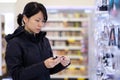 Beautiful Asian woman choosing personal care product in supermarket
